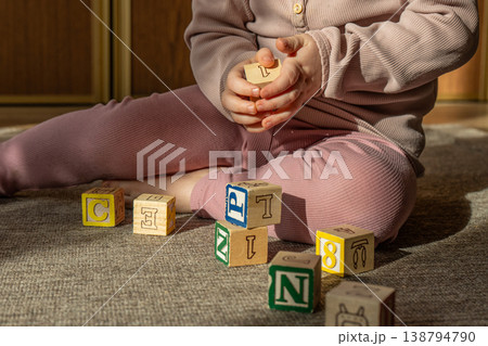 A little girl playing with colorful wooden blocks on the floor. 138794790