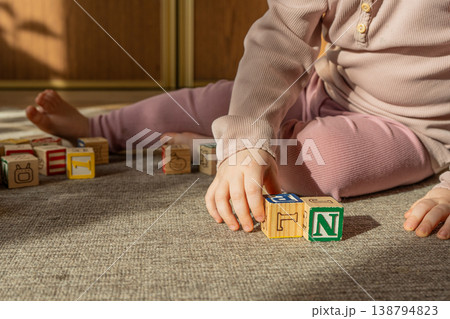 A little girl playing with colorful wooden blocks on the floor. A little girl playing with colorful wooden blocks on the floor. 138794823