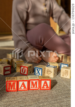 Baby stacking wooden blocks in a word mama. Concept of Mothers day. Baby stacking wooden blocks in a word mama. Concept of Mothers day. 138794829