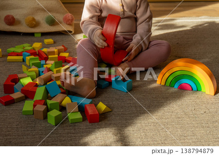 A little girl playing with colorful wooden blocks on the floor. A little girl playing with colorful wooden blocks on the floor. 138794879