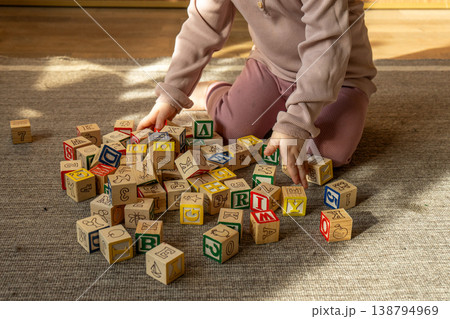 A little girl playing with colorful wooden blocks on the floor. 138794969