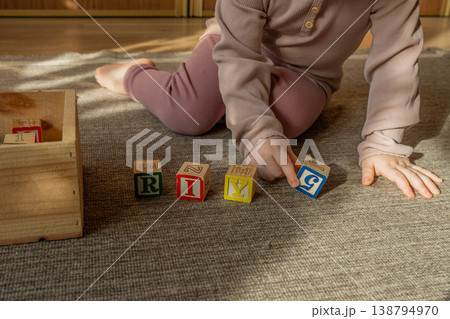 A little girl playing with colorful wooden blocks on the floor. A little girl playing with colorful wooden blocks on the floor. 138794970