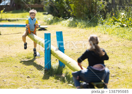 Boy playing on diy seesaw in sunny park Boy playing on diy seesaw in sunny park 138795085