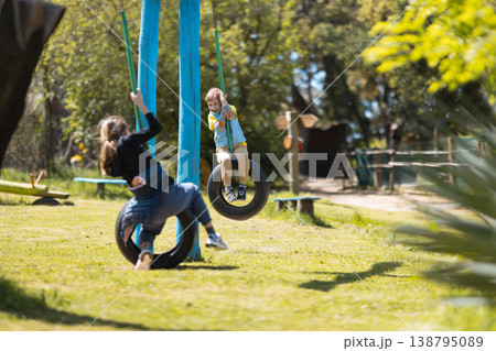Children playing together on tire swings in park 138795089