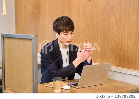 パーテーション席でイヤホンをしてPC作業に集中する男性社員 138795802