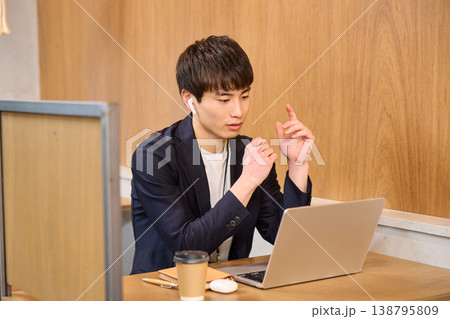 パーテーション席でイヤホンをしてPC作業に集中する男性社員 138795809