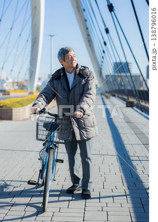 自転車を押して歩く60代男性 138796016