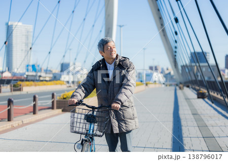 自転車を押して歩く60代男性 138796017