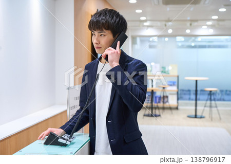オフィスの受付で内線電話をかける若いビジネスマン 138796917