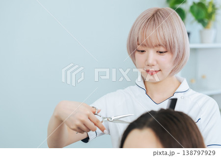 ヘアカットするハイトーンヘアの女性スタッフ ヘアカットするハイトーンヘアの女性スタッフ 138797929