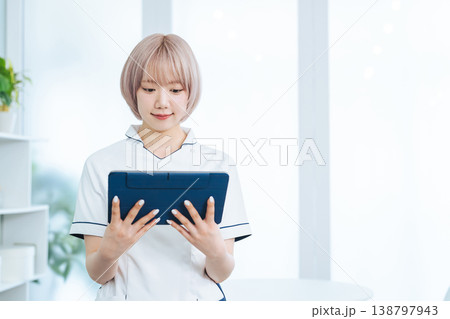 タブレットPCを見るハイトーンヘアの女性スタッフ タブレットPCを見るハイトーンヘアの女性スタッフ 138797943