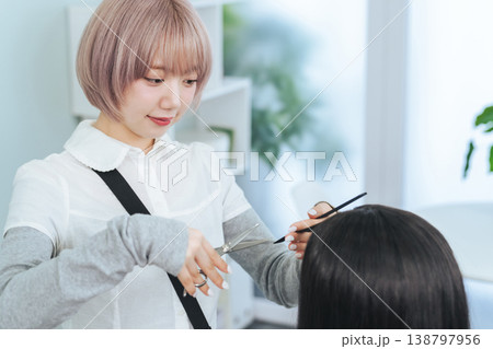 ヘアカットするハイトーンヘアの女性スタッフ ヘアカットするハイトーンヘアの女性スタッフ 138797956