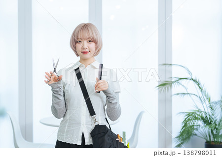 ヘアカット道具を持つハイトーンヘアの女性スタッフ 138798011