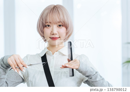 ヘアカット道具を持つハイトーンヘアの女性スタッフ 138798012