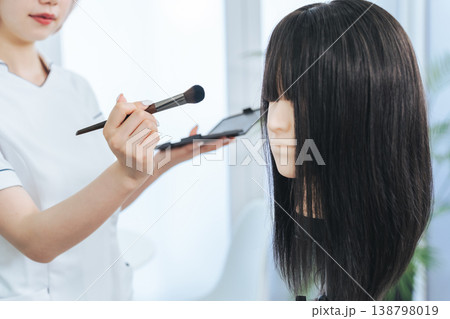 マネキンでメイクの練習をする女性スタッフ 138798019