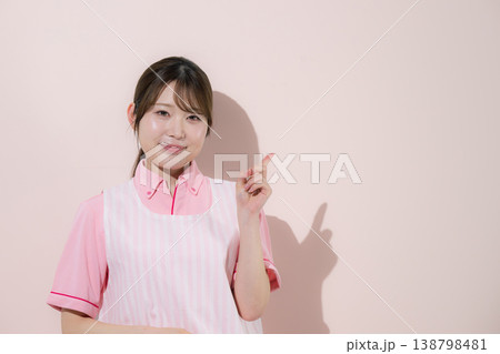 ピンク背景で介護士や保育士として働く女性の訪問介護とやりがいある仕事のイメージ 指差しでポイント ピンク背景で介護士や保育士として働く女性の訪問介護とやりがいある仕事のイメージ 指差しでポイント 138798481