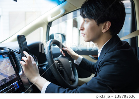 車を運転しながらスマホを操作するビジネスマン 138798636