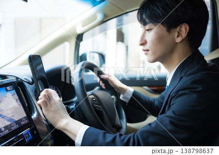 車を運転しながらスマホを操作するビジネスマン 車を運転しながらスマホを操作するビジネスマン 138798637