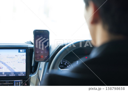 車を運転しながらスマホを操作するビジネスマン 車を運転しながらスマホを操作するビジネスマン 138798638