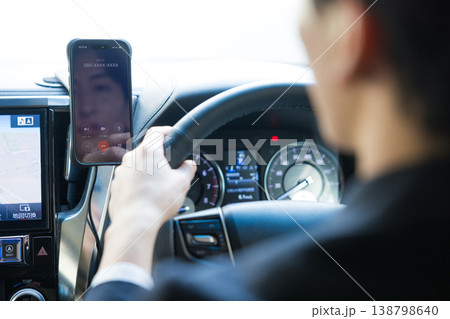 車を運転しながらスマホを操作するビジネスマン 車を運転しながらスマホを操作するビジネスマン 138798640