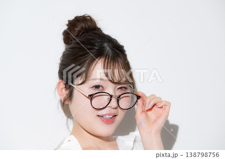 白背景で眼鏡（サングラス）が似合うお団子ヘアでかわいい美人な美容やビューティーイメージ、眼鏡ずらす 138798756
