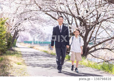 桜の下を手を繋いで歩く高校生と小学生の男の子 桜の下を手を繋いで歩く高校生と小学生の男の子 138798810