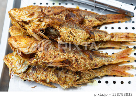 Crispy fried whole fish with golden skin stacked on tray rich texture savory flavor and traditional street food cooking style seafood ready to serve Crispy fried whole fish with golden skin stacked on tray rich texture savory flavor and traditional street food cooking style seafood ready to serve 138798832