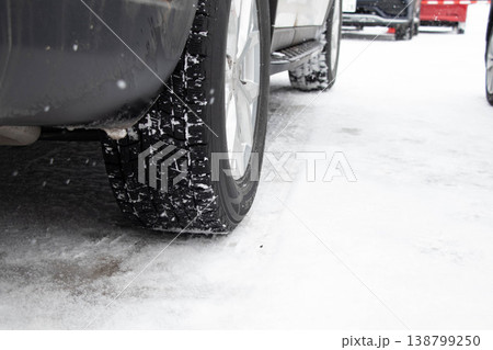 雪道を走行する車とスタッドレスタイヤのクローズアップ(冬の交通・安全イメージ) 雪道を走行する車とスタッドレスタイヤのクローズアップ(冬の交通・安全イメージ) 138799250