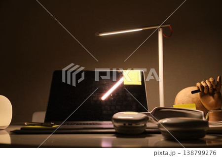 Student studying at desk with laptop and lamp at night 138799276