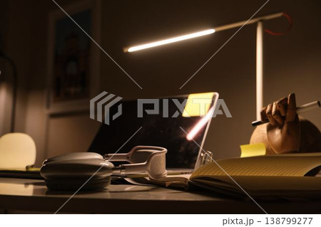 Home workspace desk with laptop and headphones studying at night Home workspace desk with laptop and headphones studying at night 138799277