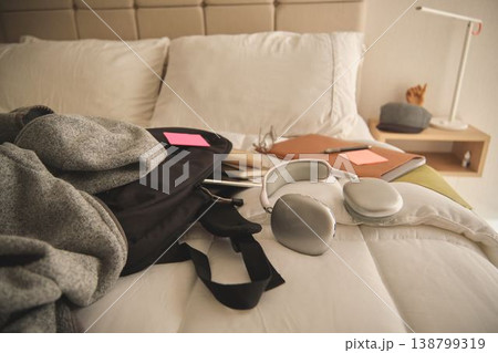 Backpack with headphones and study materials on bed Backpack with headphones and study materials on bed 138799319