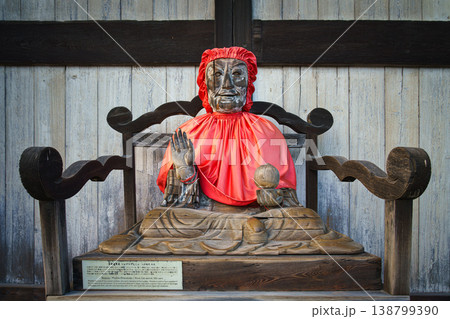 Nara, Japan - Sep 26 2024, close up view of Statue of Pindola Bharadvaja in front of Great Buddha Hall of Todaiji temple, sitting on a chair in red clothes, without people, Nara, Japan Nara, Japan - Sep 26 2024, close up view of Statue of Pindola Bharadvaja in front of Great Buddha Hall of Todaiji temple, sitting on a chair in red clothes, without people, Nara, Japan 138799390