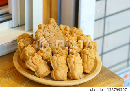 Tokyo, Japan - Sep 30 2024, A close-up view of a bowl filled with Taiyaki pies in the form of a Maneki Neko, in the window of a cafe, Tokyo, Japan 138799397
