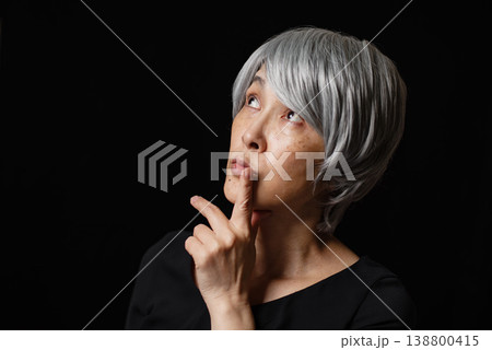 唇に人差し指を当てて考える白髪のシニア女性 138800415