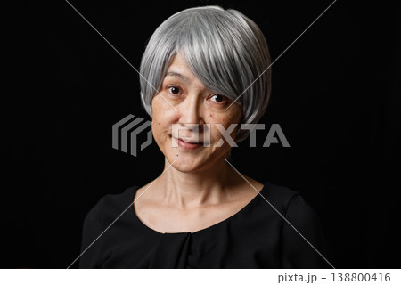 黒背景の前で微笑む白髪のシニア女性のポートレート 138800416