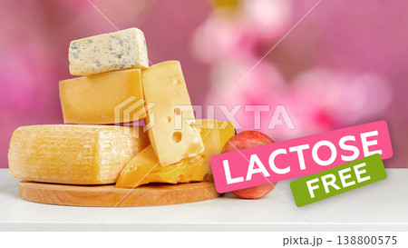 Lactose free cheese blocks stacked on a wooden board with a pink background 138800575