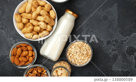 Various bowls of nuts and a bottle of milk on a dark kitchen countertop 138800589