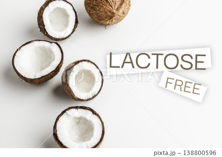 Coconuts cut open on a white surface showing lactose free label and coconut inside 138800596
