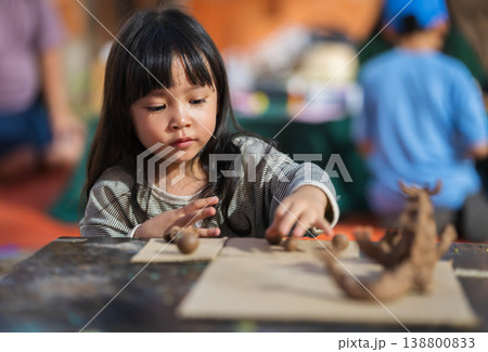 preschool child girl with sculpting from plasticine at outdoor park preschool child girl with sculpting from plasticine at outdoor park 138800833