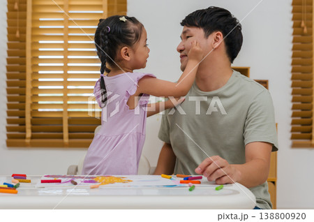happy child girl playing and painting on her father's face with oil pastels 138800920