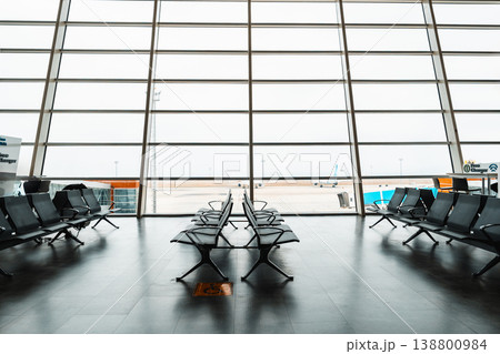 Large waiting area in an airport with empty chairs and airplanes outside Large waiting area in an airport with empty chairs and airplanes outside 138800984