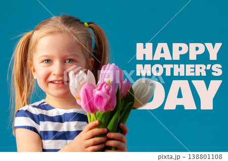 Child smiles holding flowers for Mother's Day on May 10 in front of bright blue background Child smiles holding flowers for Mother's Day on May 10 in front of bright blue background 138801108