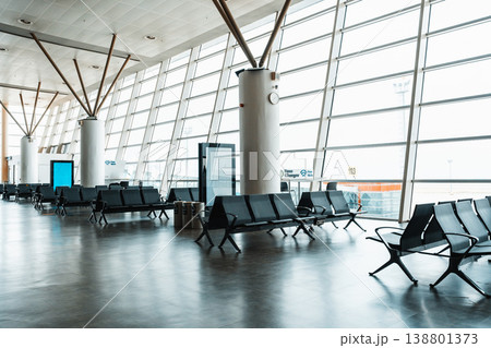 Waiting area in an airport during the day with large windows and empty seats 138801373