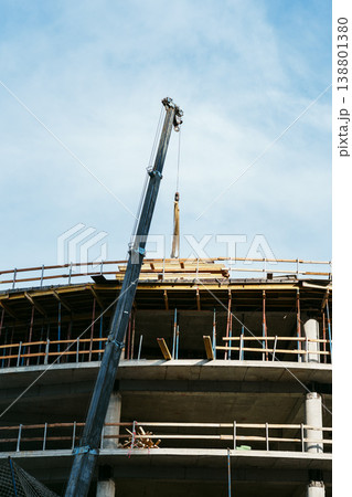 Construction work takes place at a building site with a crane lifting materials high 138801380