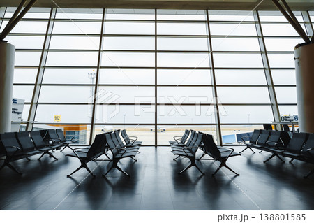 Waiting area at an airport with many empty chairs and a view outside 138801585