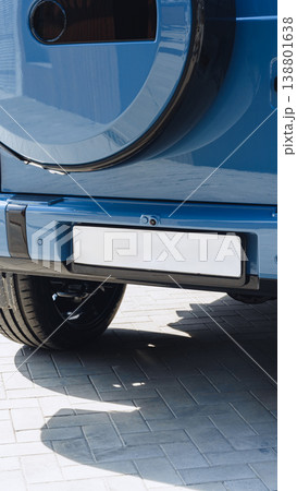Car parked on a paved surface with a focus on the rear bumper and tire at midday 138801638