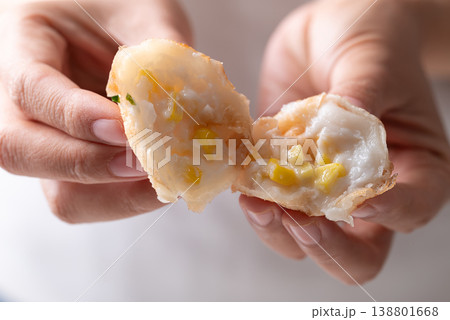 Eating Thai coconut pancakes (Kanom Krok) with corn topping by hand Eating Thai coconut pancakes (Kanom Krok) with corn topping by hand 138801668