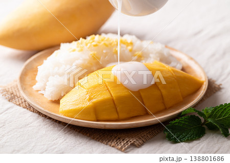 Pouring coconut milk sauce on Mango sticky rice (Khao Niew Mamuang) Pouring coconut milk sauce on Mango sticky rice (Khao Niew Mamuang) 138801686