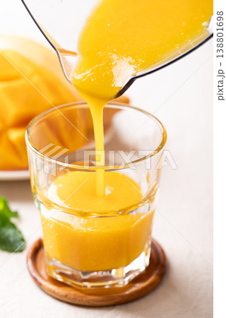 Fresh mango smoothie in a glass with ripe mango slices, refreshing summer drink Fresh mango smoothie in a glass with ripe mango slices, refreshing summer drink 138801698