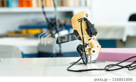 Worker uses sewing machine in workshop during day for clothing production and repairs Worker uses sewing machine in workshop during day for clothing production and repairs 138801806